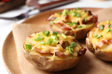 Plate of baked potatoes with cheese and bacon on table, closeup