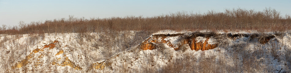 Obraz premium Winter landscape with snow. Red Clay frozen in frost. The frozen forest. Area in southern Europe. The ravines of the Budjak steppe.