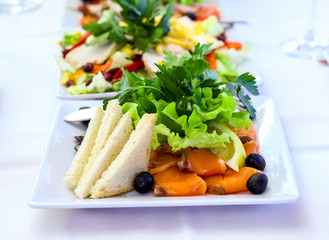 Served dishes to the table for holiday. Cutlery and food on white tablecloths in the restaurant. Design a festive Banquet. Luxurious food for guests and visitors.