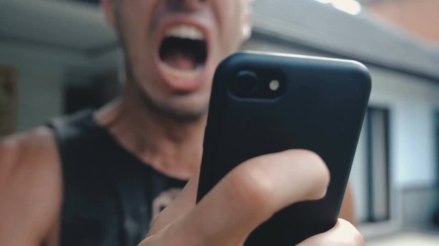 Angry Man Using Smartphone. Man is angry with the message that he read in the smartphone. Angry man uses smartphone.