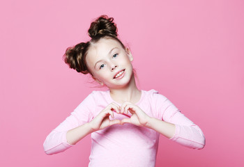  beautiful girl child over pink background smiling in love showing heart symbol and shape with hands.  