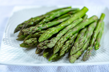 Fresh raw green asparagus vegetable on white board, close up
