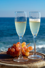 Champagne, prosecco or cava served with pink grape in two glasses on outside terrace with sea view