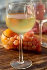 Aperitif cold white wine served in glasses with pink grapes on outdoor tessace witn sea view