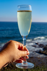 Woman hand with glas cava or champagne wine with sea view