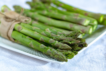 Fresh raw green asparagus vegetable on white board, close up