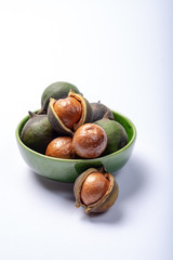 Fototapeta premium Fresh harvest of macadamia nuts, green macadamia nuts in shell close up isolated