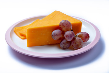 Piece of hard orange Cheddar cheese on white board isolated close up