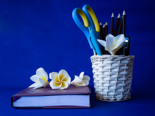 Stationery and flowers on a notebook on a blue background