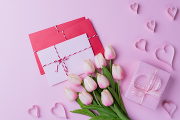 Valentines day and love concept. Pink tulips, gift box with heart and red pink letter cover on pink background.