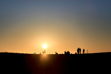 Fototapeta na wymiar Silhouettes of hikers with backpacks enjoying sunset view from top of a mountain