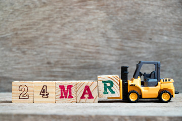 Fototapeta premium Toy forklift hold block R to complete word 24mar on wood background (Concept for calendar date 24 in month March)