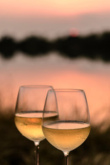 A romantic dinner in summer on a beach at sunset with two glasses of white wine