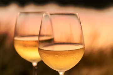 A romantic dinner in summer on a beach at sunset with two glasses of white wine