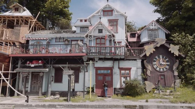Woman knocking the main door of a wooden antique house. Picturesque house with colorful paint and beautiful details of construction. 4k