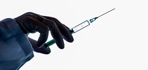 a hand with glove holds a syringe for vaccination