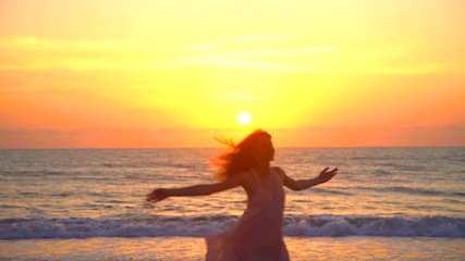 Cute Caucasian American girl dancing on holiday beach at sunset 