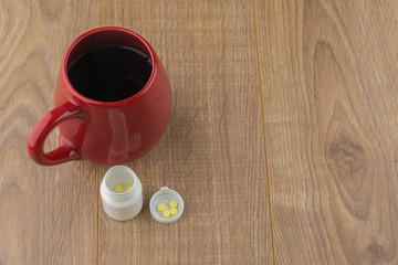 the struggle against Drowsiness : caffeine pills near the pill boxes and red Cup of strong coffee on wooden table