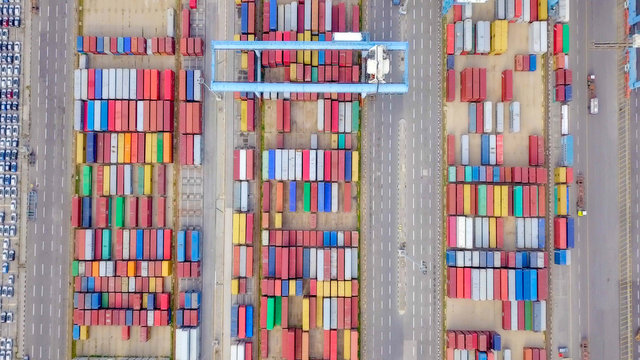 Transtainer yard - Various brands and colours of Shipping containers stacked by Transtainers (Mobile gantry cranes) off of service trucks - Top down aerial image