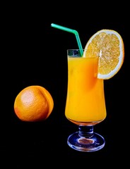 A orange juice in a glass with an orange beside