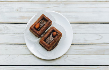 Two muffins with almonds on white dish on grey rustic wooden background. Top view, copy space.