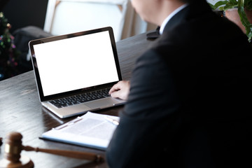 Man working by using a laptop computer on wooden table. Hands typing on a keyboard.