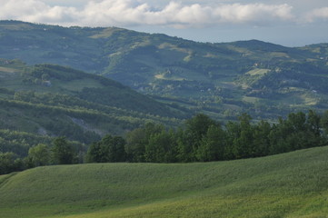 Fototapeta premium Hills and fields with loose buildings during sunset in northern Tuscany, Italy.