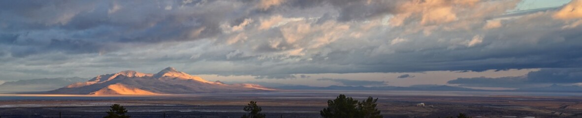 Antelope Island view from Magna, sweeping cloudscape at sunrise with the Great Salt Lake State Park in winter. USA, Utah.