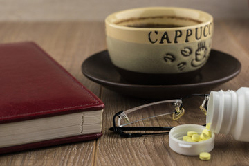 nighttime reading, self-education: Tablets of ephedrine, coffee, glasses and book on a wooden table