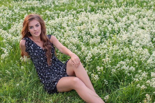 Young Lady Sitting Outdoors In A Field Of White Flowers.