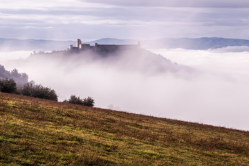 Fototapeta na wymiar A view of Rocca Maggiore castle in Assisi (Umbria, Italy) in the middle of fog