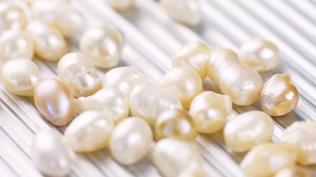 White and gold pearls on metal surface. Close up of jewelry 4k footage.