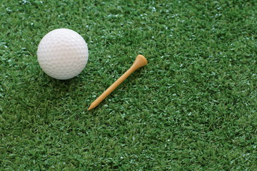 Golf ball and tee on green lawn background