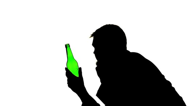 Alcoholic sits with a bottle in his hands and drinks. Side view. Silhouette White background