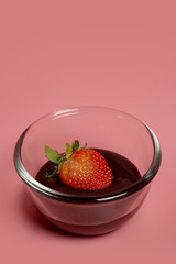 fondue strawberry soaked in hot black chocolate on a fork with pink background with minimalist style .have some spec for write wording