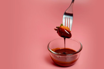 fondue strawberry soaked in hot black chocolate on a fork with pink background with minimalist style .have some spec for write wording