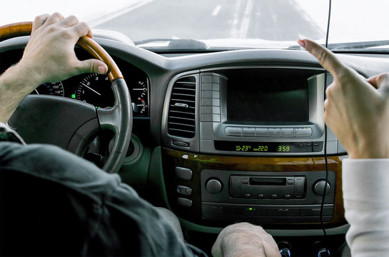 Hand Of The Girl, Points A Finger To The Man, Driver, At The Moment When He Is Driving A Car, In The Winter, In The Snow-covered Mountainous Terrain On A Slippery Road