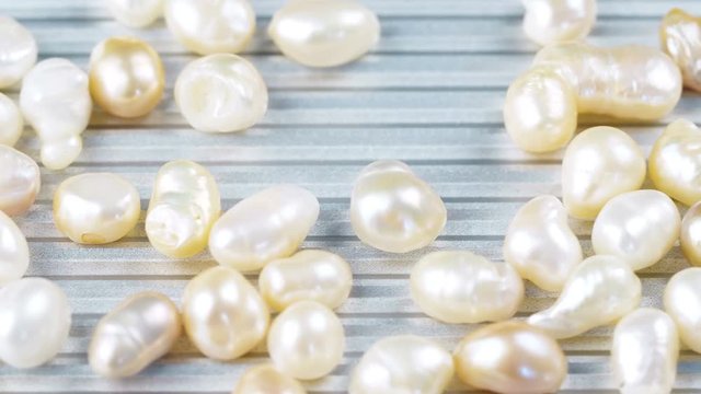 White and gold pearls on metal surface. Close up of jewelry 4k footage.