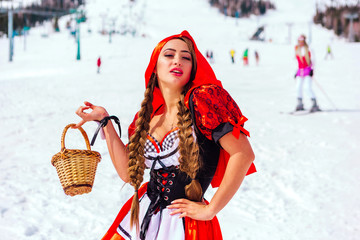 Little Red Riding Hood with wicker basket and kruasan on the snowy winter slope