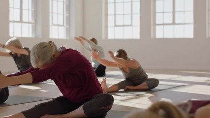 yoga class of healthy mature woman practicing head to knee forward bend pose enjoying morning physical fitness workout in studio