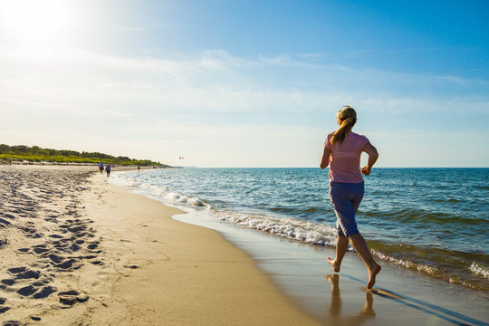Middle-aged woman running on beach