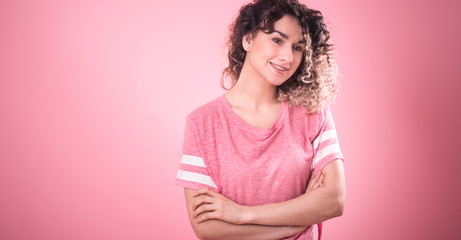 Fototapeta premium Portrait of a beautiful cheerful girl with curly hair on a pink background