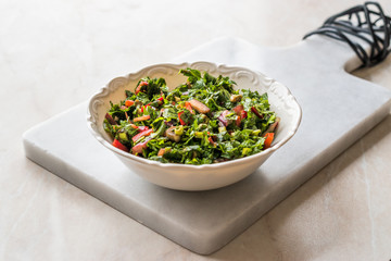 Chopped Parsley Salad with Tomatoes and Onions in Ceramic Bowl on Marble Board.