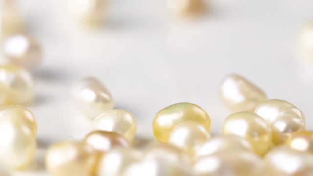 Natural golden pearl falling down in slow motion. Close up macro 4k footage.