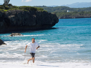 A man runs along the beach of the ocean. Sunny day and big waves.