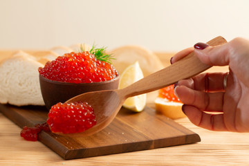 red caviar in a ceramic dish on a wooden background in a rustic style with space for text