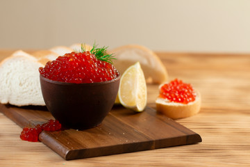 red caviar in a ceramic dish on a wooden background in a rustic style with space for text