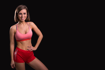 Fototapeta premium Slim athletic girl smiling at you on a black background