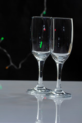 empty wine glass close-up on a black background with a place for text on the background of Christmas lights
