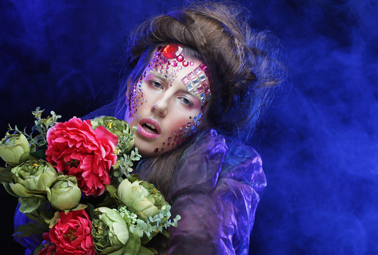  young woman with creative make up holding flowers